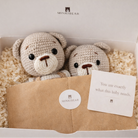 Crocheted teddy bear and rattle set inside MINKIBEAR white gift box with ivory crinkle paper